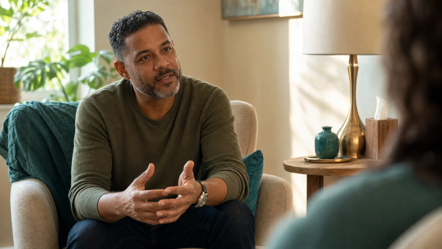 A man in an armchair talking with a therapist, engaged and at ease